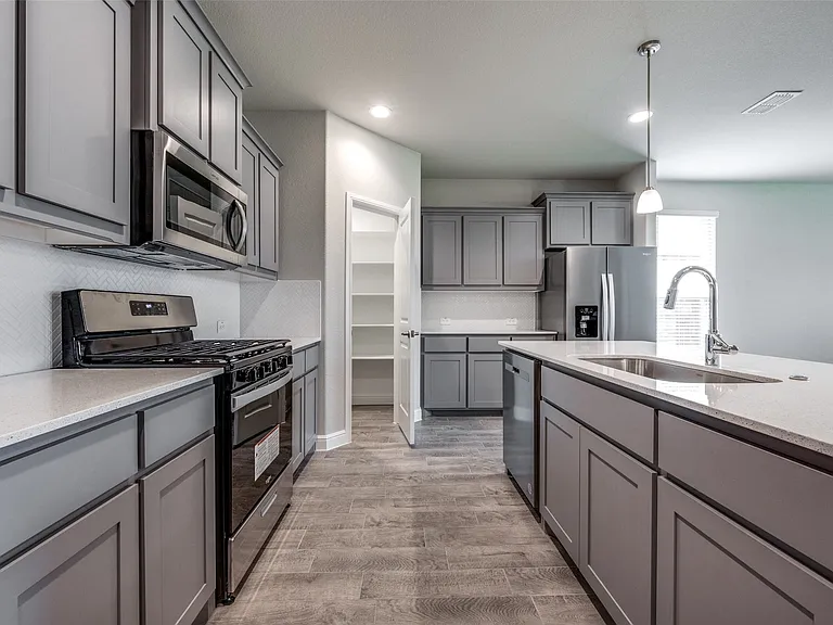 Kitchen featuring tasteful backsplash, stainless steel appliances, decorative light fixtures, light wood-type flooring, and sink