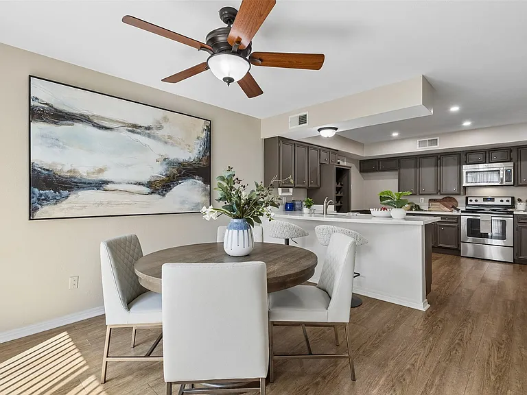 Dining area with wood-finish flooring featuring a wood-tone ceiling fan and sliding glass doors to the patio.