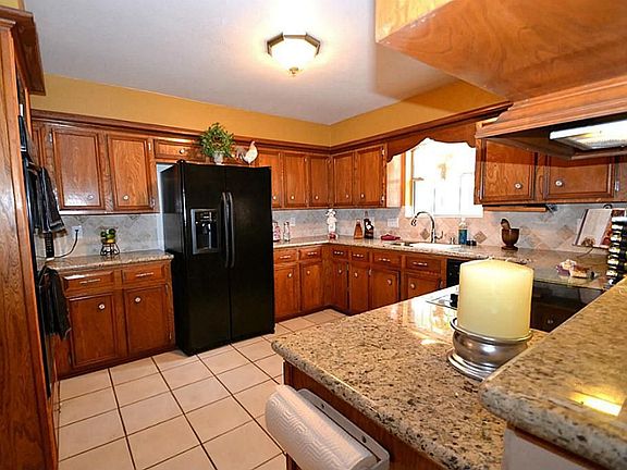  Kitchen offering tile floors, tumbled marble backsplash, granite counter tops, flat surface cook top, built-in double oven, pantry and a breakfast bar.