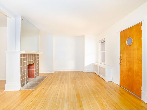 A view of the front door and living room. Everything has been freshly repainted and all of the hardwood floors have been sanded and resealed. The dining room is through the archway on the left.