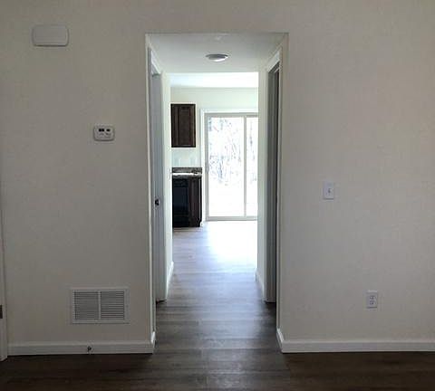 hallway from living room to half bath on right and laundry room/utility room on left to full kitchen with appliances and walk out patio