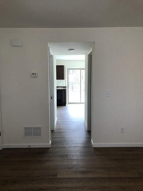 hallway from living room to half bath on right and laundry room/utility room on left to full kitchen with appliances and walk out patio