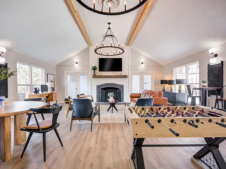 A lofted clubhouse featuring a fireplace, grand chandelier, comfortable seating area, and foosball table are shown at ReNew on Cantrell.