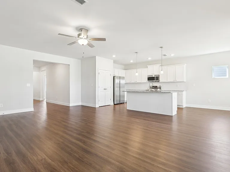 Spacious kitchen equipped with a refrigerator, sink, and ceiling fan leading into the living room