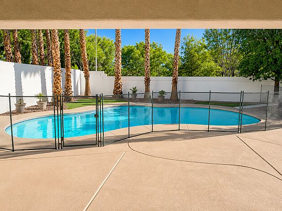 Private backyard with sparkling pool, safety fence, and spacious pool deck