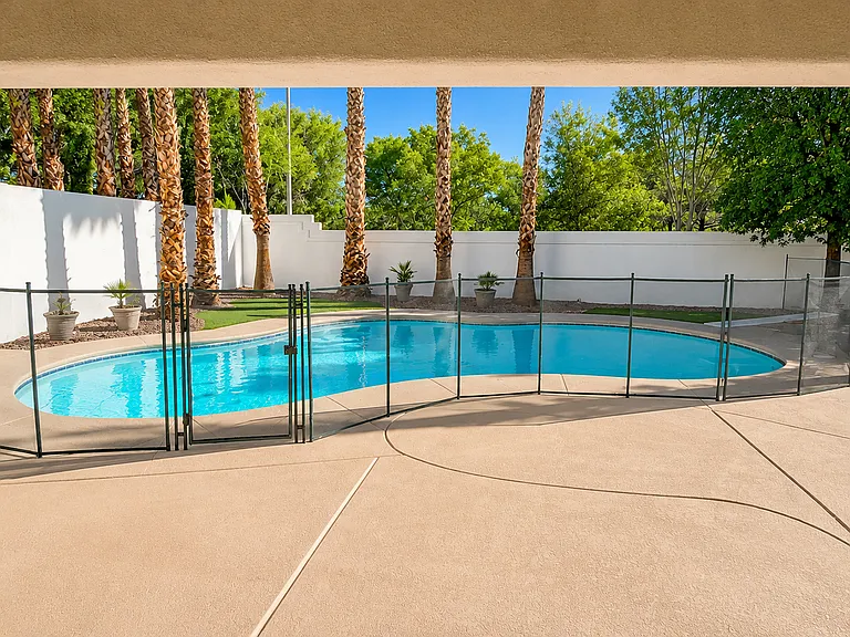 Private backyard with sparkling pool, safety fence, and spacious pool deck
