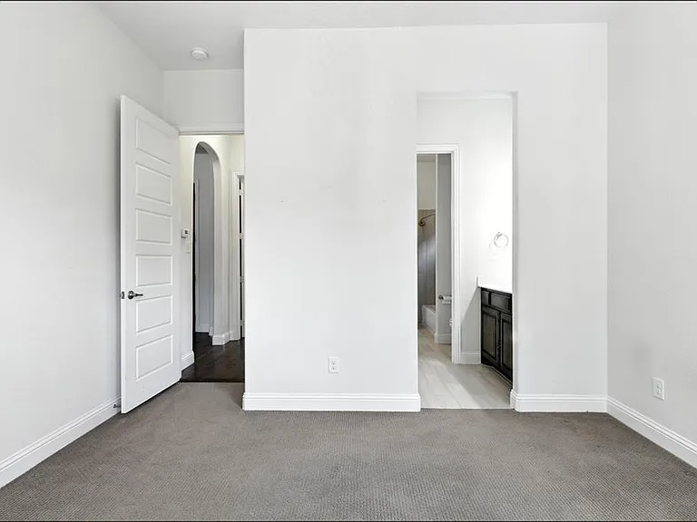 Carpeted room with white baseboards and walls