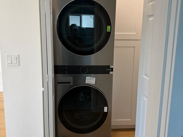 Full sized washer and dryer in hall closet with floor to ceiling cupboards