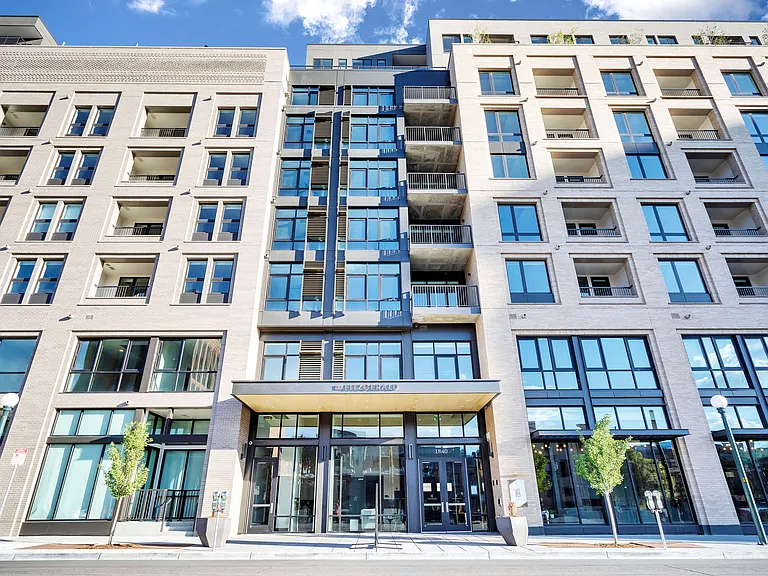 Modern apartment building exterior with sleek glass windows, inviting balconies, and stylish entrance in a sunny urban setting.
