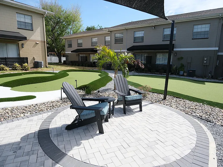 Inviting outdoor patio with cozy Adirondack chairs overlooking a beautifully landscaped mini-golf course, perfect for relaxation and leisure.