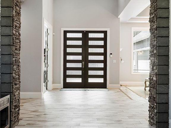This stunning foyer has soaring cathedral ceilings,beautiful custom tile that looks like wood flooring! Stone accent wall welcomes you into the formal living area.>