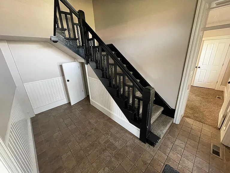 Front door entryway foyer with historic staircase and small closet underneath