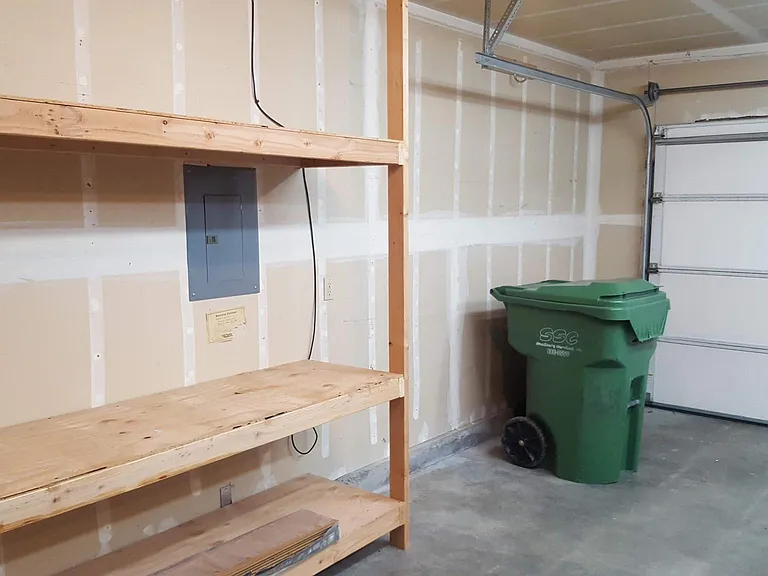 Garage has great lighting and multiple shelving areas