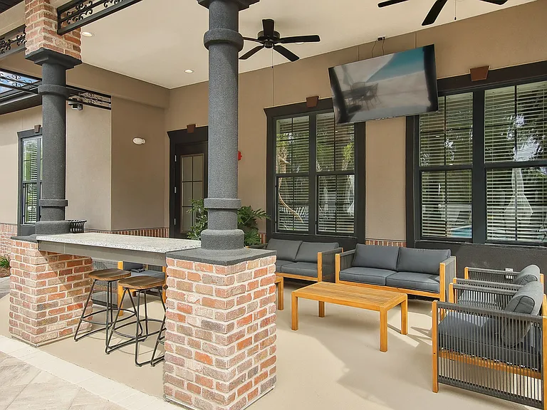 Elegant outdoor patio featuring cozy seating, brick columns, and a sleek bar area, perfect for leisure and entertaining.