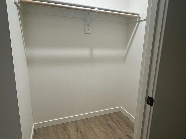 Dedicated walk-in closet with hanging rod and open upper shelf for easy organization and added storage.