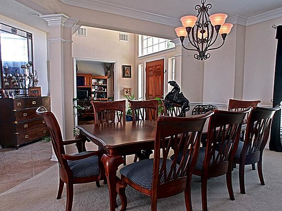 The Formal Dining Room has double crown molding, chair railing, decorative columns that define this space, soft neutral carpet, and a picturesque window that allows a hint of natural light to the room.