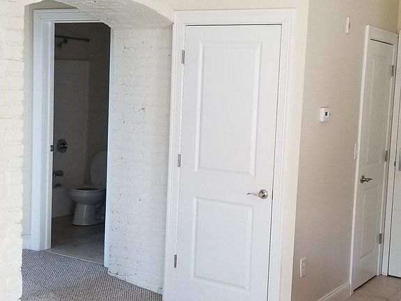Archway to the hall, Brick accent wall, and laundry closet