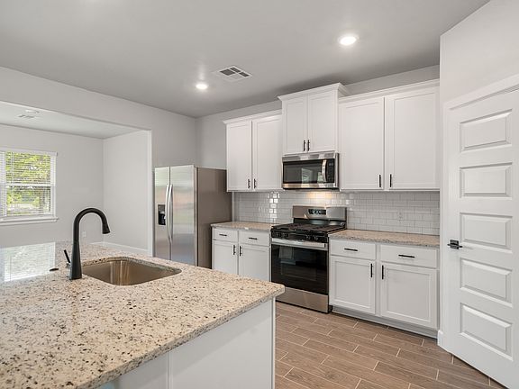 The beautiful kitchen has white wood cabinetry and tile backsplash.
