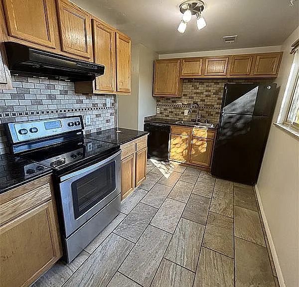 Modern kitchen with stainless steel appliances, wooden cabinetry, and elegant tile flooring.