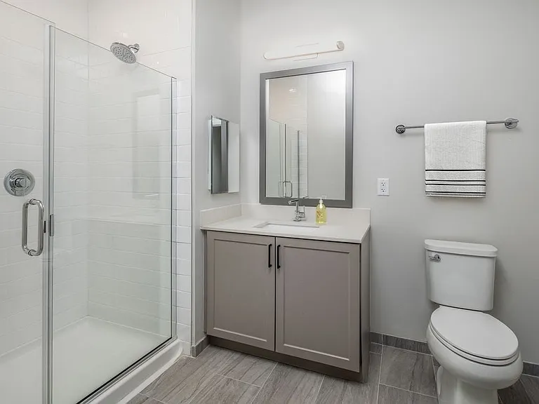 Upgrade Scheme bath with white quartz countertops, grey cabinetry, and hard surface flooring