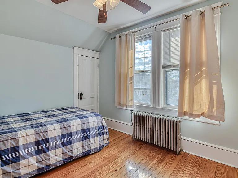 South-facing front bedroom has twin size bed, bedside table, dresser, ceiling fan & closet. This bedroom also has dedicated work space with desk and chair.