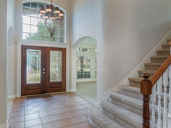 Stunning entryway with leaded-glass double mahogany front doors, large window, and graceful chandelier greet everyone upon arrival and welcome them to your beautiful home!