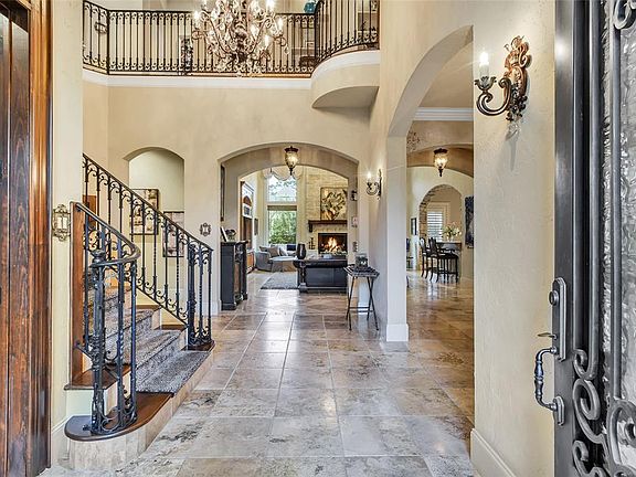 Beautiful entryway into large foyer with Travertine flooring, soaring ceilings and dramatic curving wrought iron staircase.