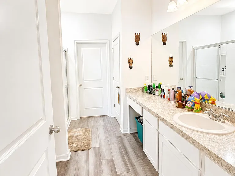 Spacious bathroom with an extended vanity, ample counter space, large mirror, and durable tile flooring for easy upkeep.