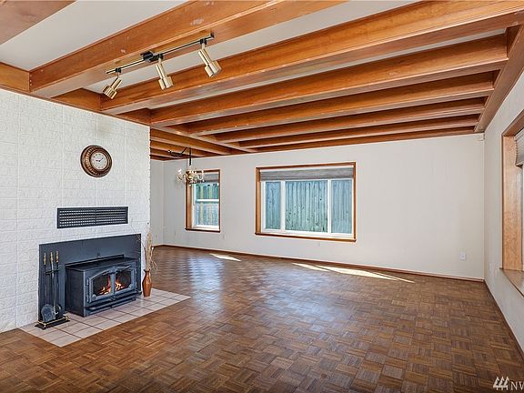 Living room has wood fireplace insert and hardwood parquet floor