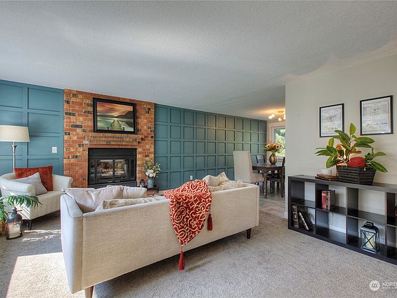 Beautiful formal living room with wood burning fireplace and stunning feature wall. Newer carpet.>