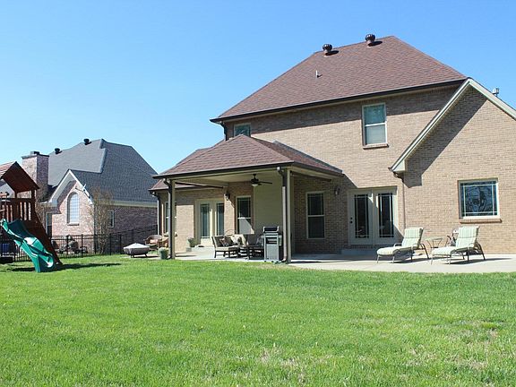 Large Fenced Yard, with large concrete patio, middle portion is covered with a fan.