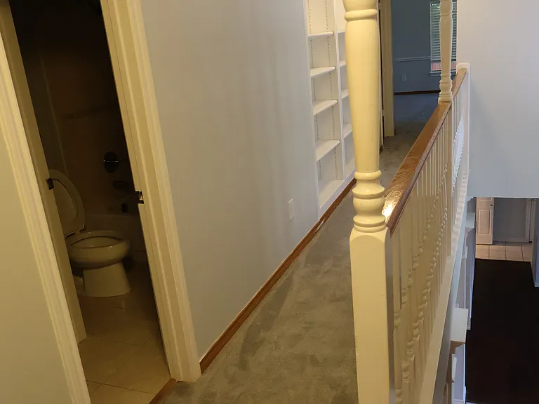 Upper hallway looks out on the entry way. It has a built-in bookcase.