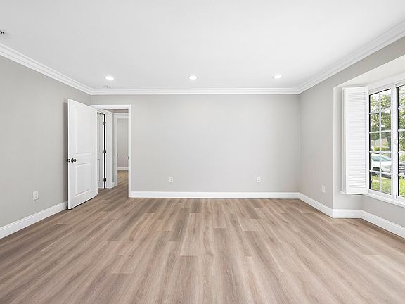 Living room with brand-new hard wood floor, freshly painted wall and recessed ceiling light.