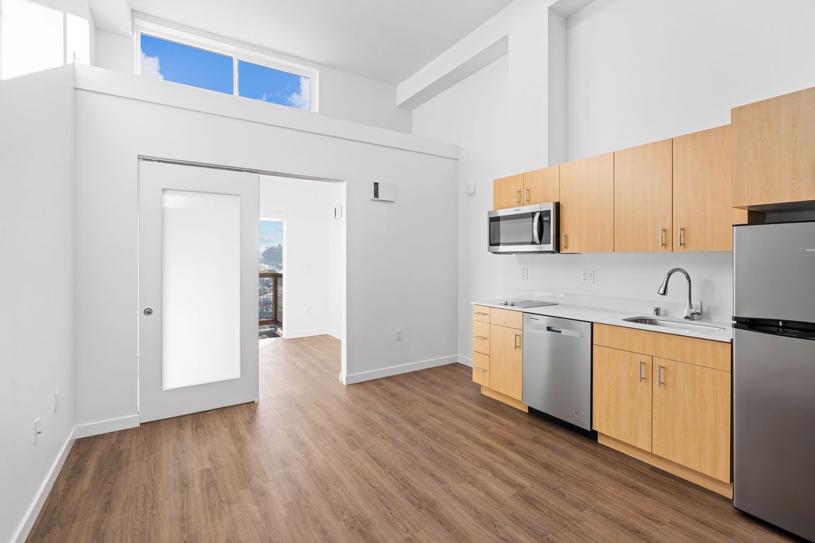 Enjoy cooking in this modern kitchen featuring sleek wood flooring, ample cabinet space, and a clean, open design.