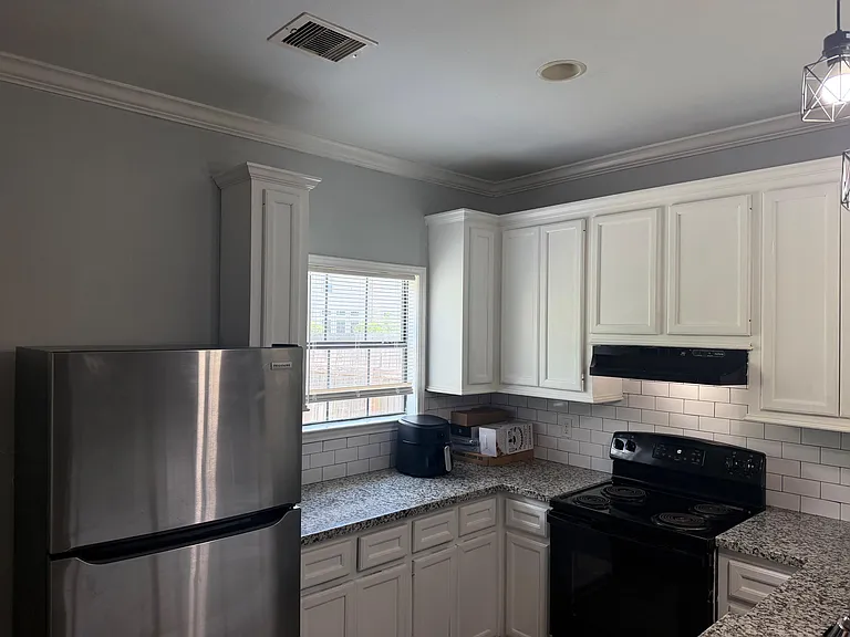 Efficient kitchen with ample white cabinetry, granite-look counters, subway-tile backsplash, and full-size appliances.