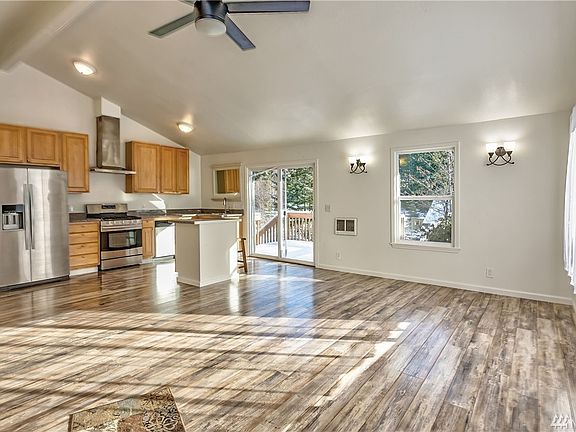 Open concept kitchen with gas range, large fridge, island and remote controlled fan.