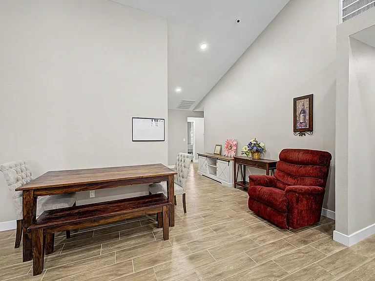 Open dining area with a solid wood table, bench seating, and adjacent lounge nook on durable tile flooring.