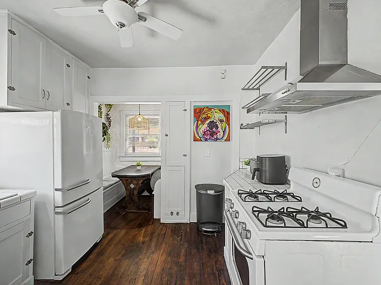 Compact kitchen with gas range, vent hood, ample cabinetry, and adjoining breakfast nook with window seating.