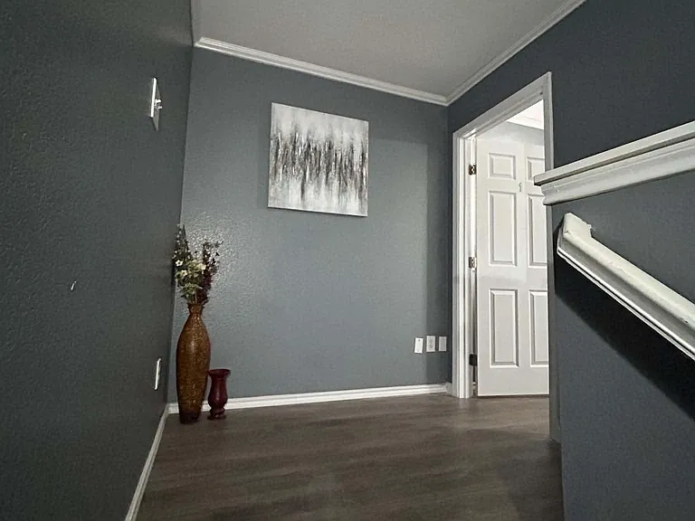 Freshly finished stair landing with durable wood-look flooring, tall ceilings, and easy access to adjacent rooms.