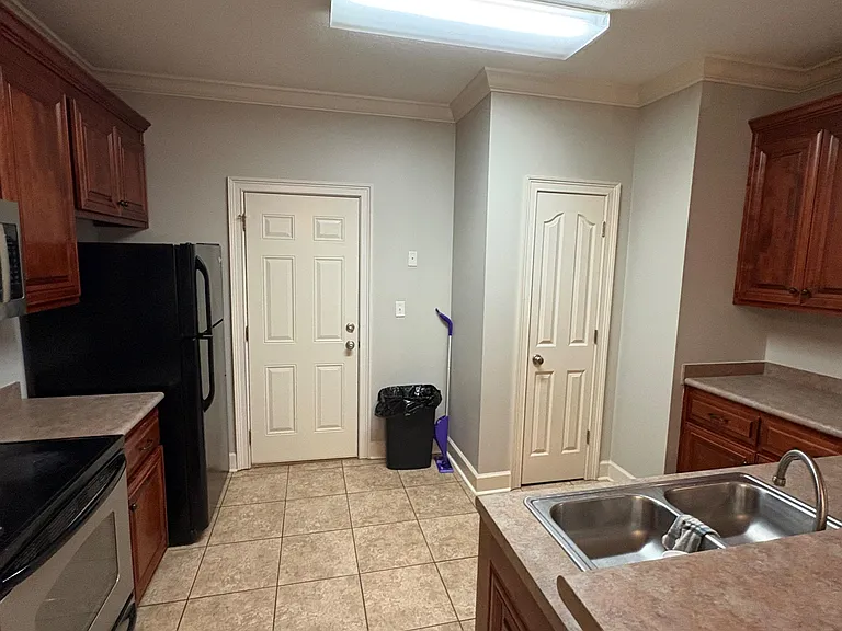 Eat-in kitchen with ample wood cabinetry, laminate counters, and a full appliance set including refrigerator and range.
