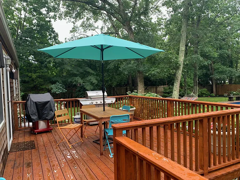 Larger deck with grill and dining connected by kitchen door
