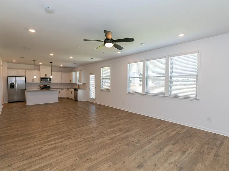 Spacious kitchen equipped with a refrigerator, sink, and ceiling fan leading into the living room