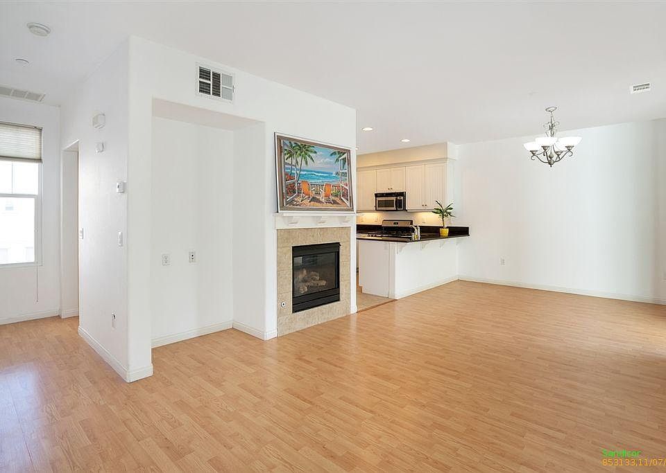 Open-concept living/dining/kitchen. Balcony to right, out of frame. Flooring has been replaced with luxury vinyl plank.