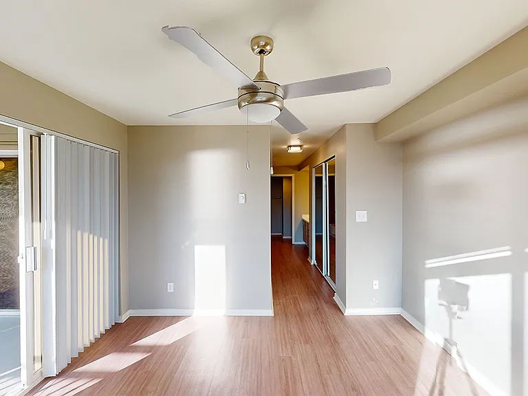 Spacious apartment bedroom with attached bathroom and wood-style flooring.