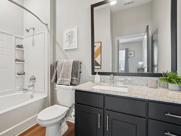 Bath with dark cabinetry, speckled granite countertops, and hard surface flooring