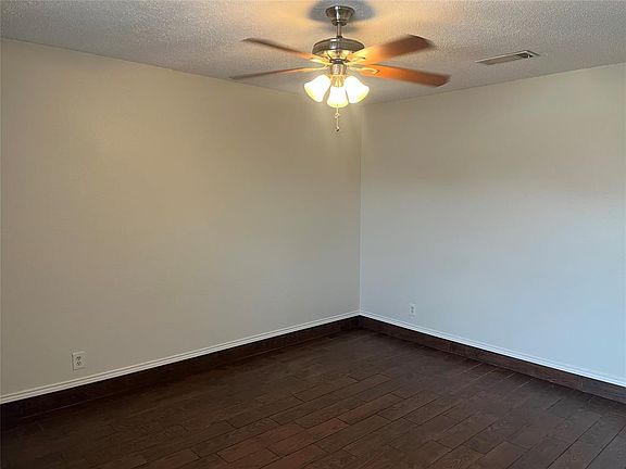 Bedroom with a textured ceiling, visible vents, baseboards, ceiling fan, and wood-style floors