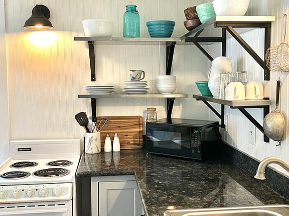 Counter is beautiful black granite. Microwave, toaster, blender, coffee maker, and hand mixer are all included.