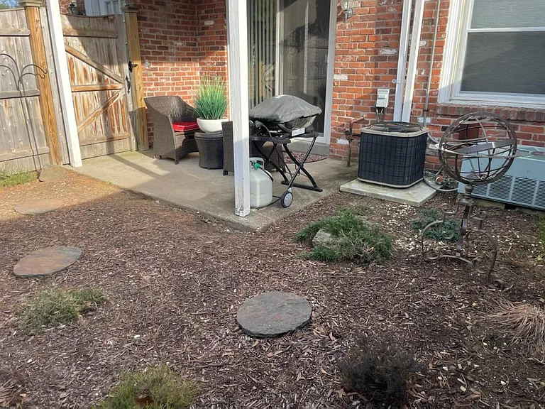 Sliders from living room to private fenced small patio with landscape