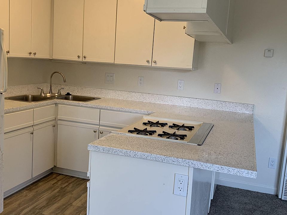 Kitchen with plank style flooring, white cabinets, and gas range at Carlsbad Sunset Senior Apartments in Carlsbad, California.