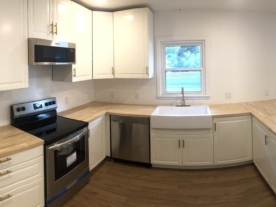 kitchen with butcher block countertop, farmhouse sink, electric stove and oven, microwave, dishwasher, refrigerator